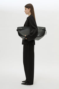 Styled view CAMILLA AND MARC Willa Tote in Black with side strap and buckle detailing and magnetic button closure.